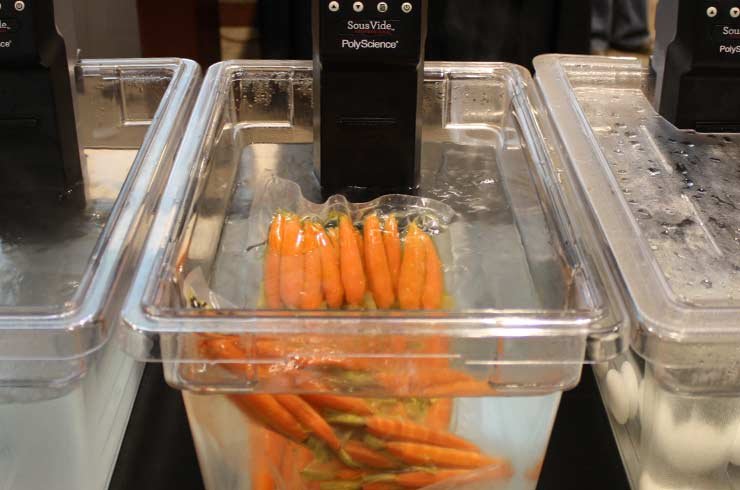 Legumes variados cozinhando no sous vide — técnica que preserva sabor, textura e nutrientes.